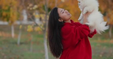 Beyaz tükürük köpekli Asyalı kadın, sonbahar ağır çekim portresi.