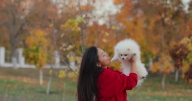 Beyaz tükürük köpekli Asyalı kadın, sonbahar ağır çekim portresi.