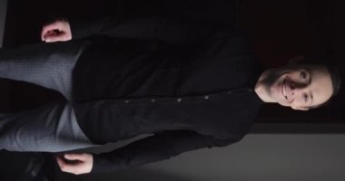 Gülümseyen ve komik bir adam klasik takım elbise giyip içinde dikey poz veriyor.