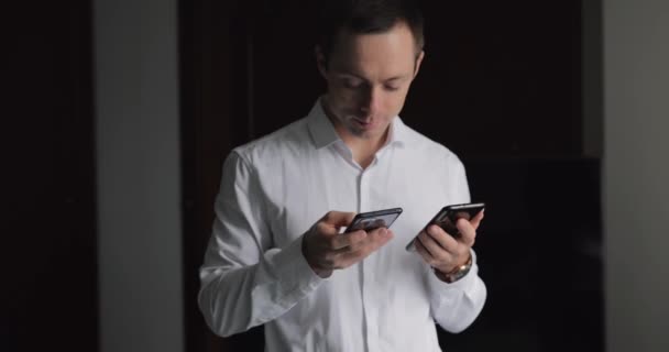 Pencerenin Yanındaki Klasik Takım Elbiseli Adamını Kullanan Iki Cep Telefonu — Stok video