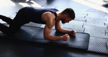 Sporcu spor salonunda tahta egzersizi yapıyor.