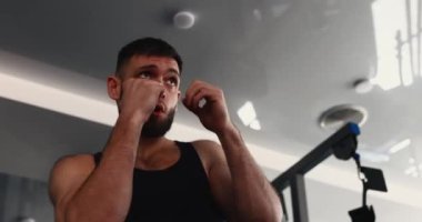 Gölgelerle dövüşen bir adam, spor kulübünde boks yapıyor.