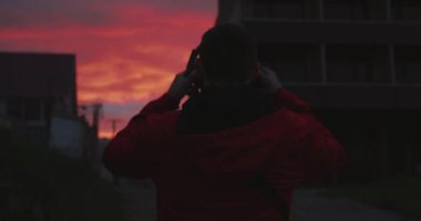 Güzel kırmızı gün batımında kulaklık takan adam.