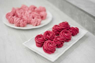 Tabakta bir sürü kırmızı ve pembe marşmelov var.