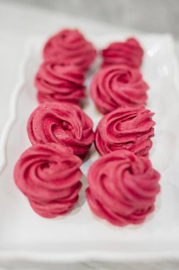 Tabakta bir sürü kırmızı ve pembe marşmelov var.