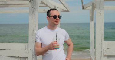 Plajda mojito tutan adam, yüzünü dön ve gülümse, ağır çekimde.