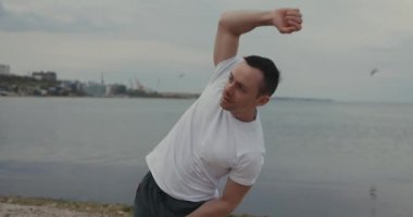 Yakışıklı adam sahildeki antrenmandan önce ısınıyor.