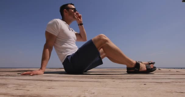 Чоловік Сонцезахисних Окулярах Сидить Природі Біля Моря Розслабляється Літній День — стокове відео