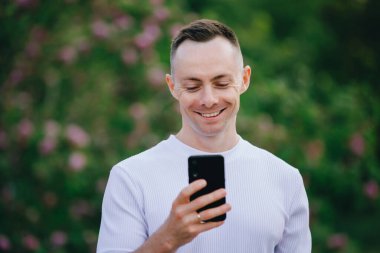 Yakın plan yakışıklı beyaz adam yaz günü cep telefonuna bakıyor.