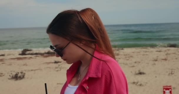 若いです女性でピンク飲む新鮮なモヒート歩くとビーチ スローモーション — ストック動画