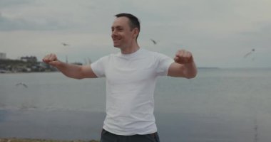 Yakışıklı adam sahildeki antrenmandan önce ısınıyor.