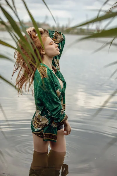 stock image Portrait of naked woman in green shirt standing at the river touching hair