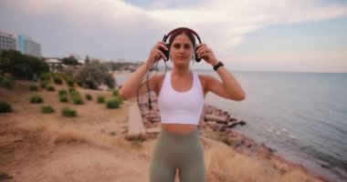 Denizde kulaklık takan ve müzik dinleyen bir kadın.