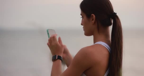 Piękna Sportowa Kobieta Wystrojona Patrząc Telefon Morze Tle — Wideo stockowe