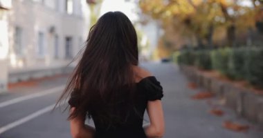 Gülümseyen kadın yüzünü geriye dönerek sonbahar geçidinde yürüyor.