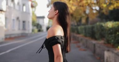 Ağır çekimde güzel bir kadın yüzünü geriye çevirir ve saçlarını savurur sonbahar geçidinde yürürken