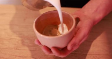 Kahveci latte hazırlamak için bardağa süt dolduruyor.