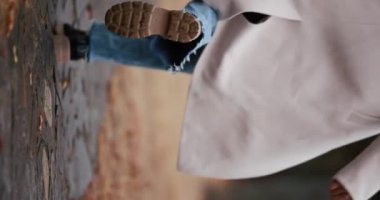 Arka planda koşan mutlu kadın sonbahar gününün tadını çıkarıyor, yavaş çekim dikey video.