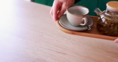 Garson bir restoranda masada bitki çayı servis ediyor.