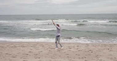 Mutlu adam küçük bir çocuk gibi ellerini kaldırarak denizin tadını çıkarıyor.
