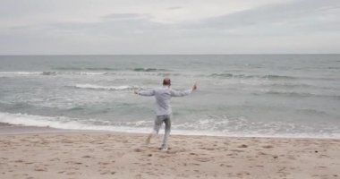 Mutlu adam küçük bir çocuk gibi ellerini kaldırarak denizin tadını çıkarıyor.