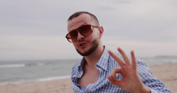 Homem Mostrando Gesto Sentado Praia Mar — Vídeo de Stock