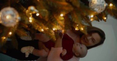 Noel ağacını Noel 'den önce tutan ve süsleyen kadın dikey video.