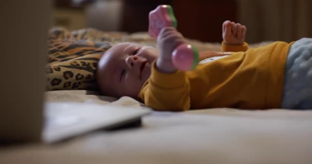 漂亮的小男孩躺在床上抱着 玩着婴儿的响尾蛇 — 图库视频影像