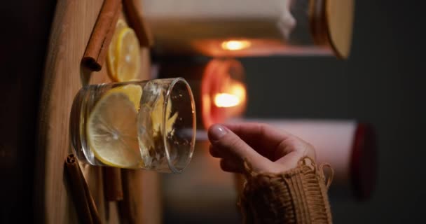 レモン付きの水 女性の手は 水のガラスにレモンを追加 垂直ビデオ — ストック動画