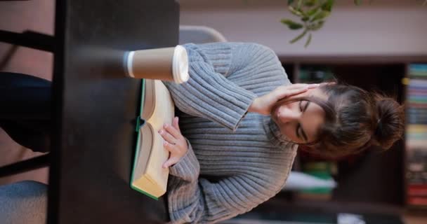 Młoda Kobieta Czytająca Książkę Pijąca Kawę Siedząca Kawiarni Przy Stole — Wideo stockowe