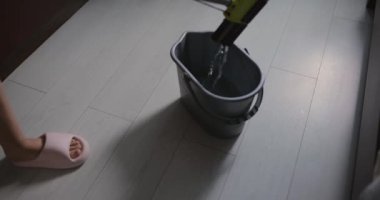 Tanımlanamayan kadın parke zemini paspasla temizliyor.