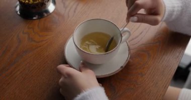 Kadın elleri şekeri karıştırıyor ve kafede çay içiyor.