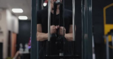 Spor salonundaki blok egzersizinde triseps yapan tanınmamış bir adam.