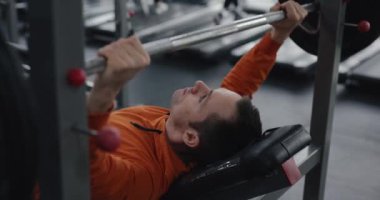 Spor salonunda göğüs presi yapan bir adam.