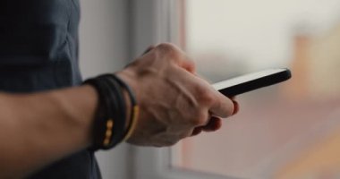 Cep telefonu kullanarak bileklik takan erkeklerin yakın plan fotoğrafları.