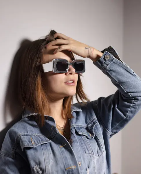 Sıra dışı gümüş güneş gözlüğü takan genç bir kadın.