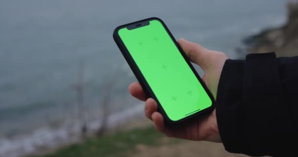 Mão Masculina Segurando Smartphone Com Tela Verde Chromakey Mar — Vídeo de Stock