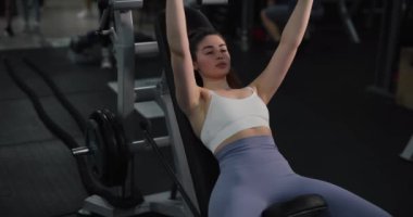 Spor salonunda göğüs egzersizi yapan bir kadın.