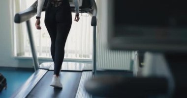 Spor salonunda koşu bandında egzersiz yapan bir kadın.