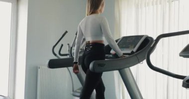 Spor salonunda koşu bandında egzersiz yapan bir kadın.
