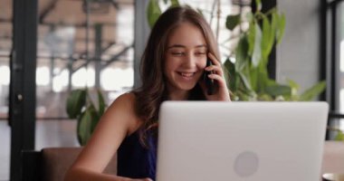 Bir kafede çalışan ve bilgisayarla konuşan serbest çalışan bir kadın.