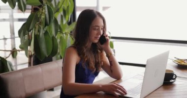 Bir kafede çalışan ve bilgisayarla konuşan serbest çalışan bir kadın.