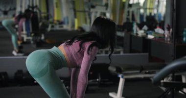 Antrenman kasları, spor salonunda halterle kalça hareketi yapan bir kadın.