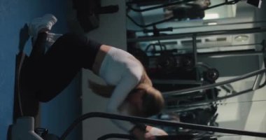 Antrenman kasları, spor salonunda egzersiz yapan bir kadın, dikey video.