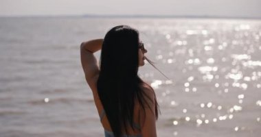 Kadının silueti denize bakıyor, geriye bakıyor, yavaş çekim.