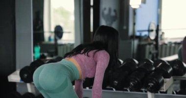 Antrenman kasları, spor salonunda halterle kalça hareketi yapan bir kadın.