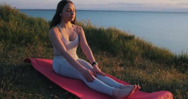 Yoga yapan kadın, pelerin üzerindeki mindere uzanır, ağır çekimde.