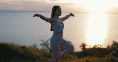 Yoga yapan kadın doğada tek ayak üstünde duruyor.