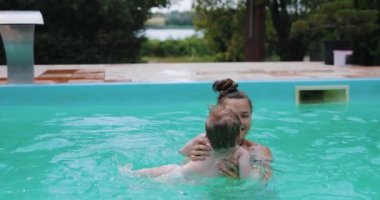 Küçük oğluyla havuzda eğlenen genç bir kadın.