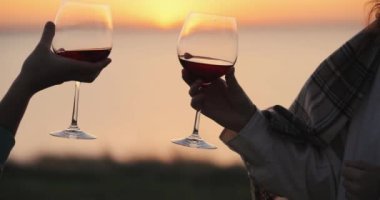 Gün batımında kadın kadehleri şarapla tokuşturur, ağır çekimde